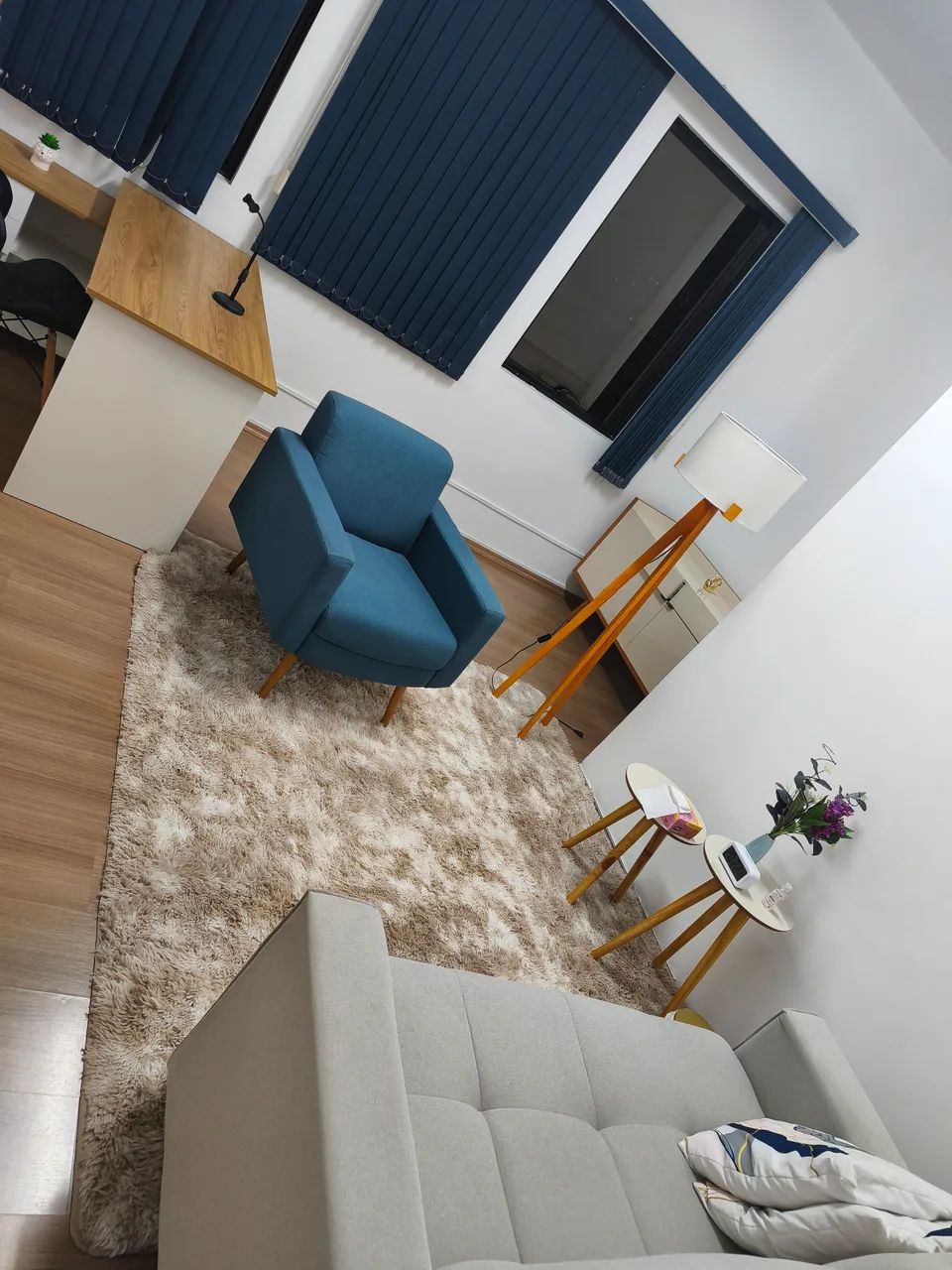 Sala de atendimento com poltrona azul, sofá e iluminação de apoio
